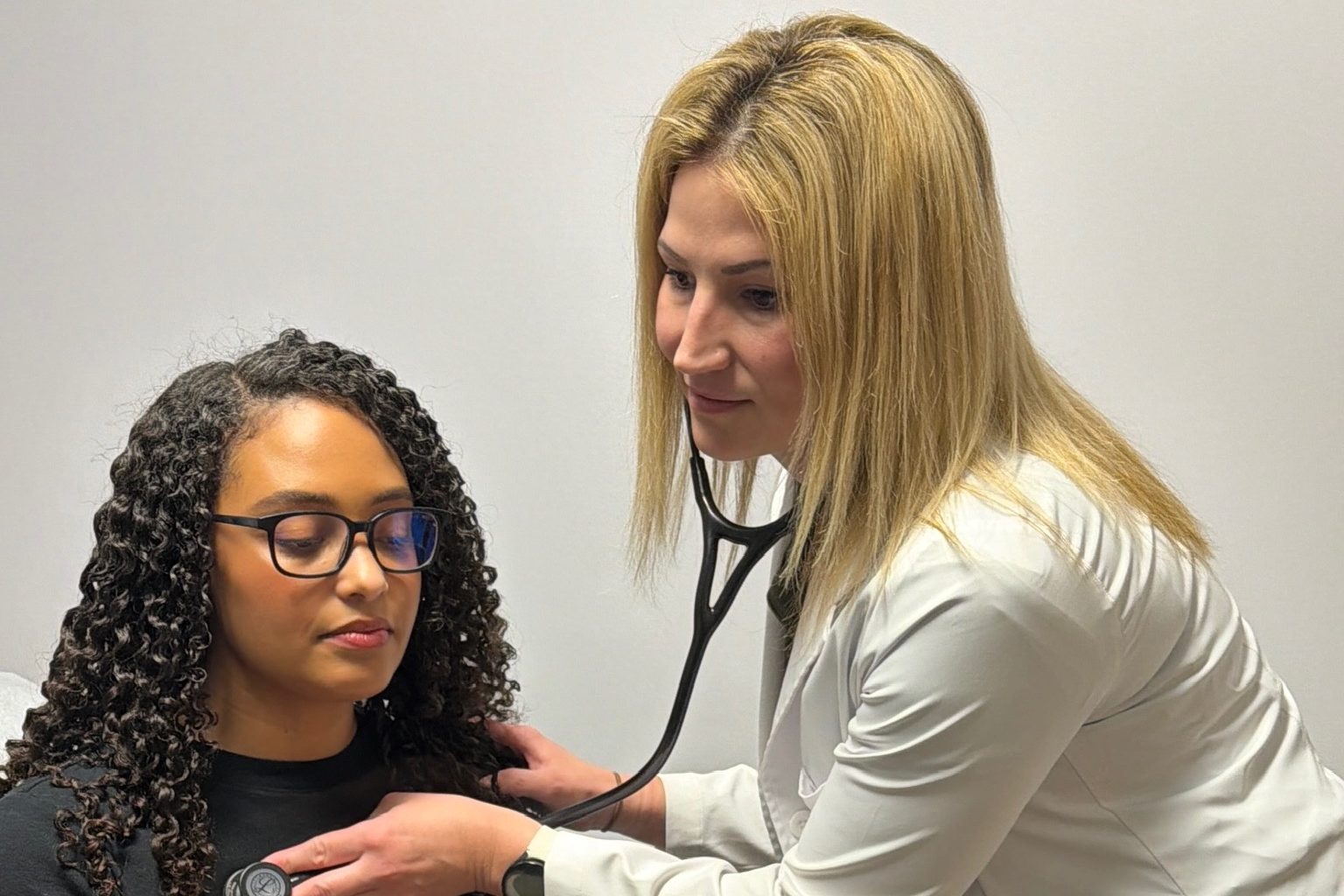 A Transmountain Primary Care provider listening to a patient's heart with a stethoscope in El Paso