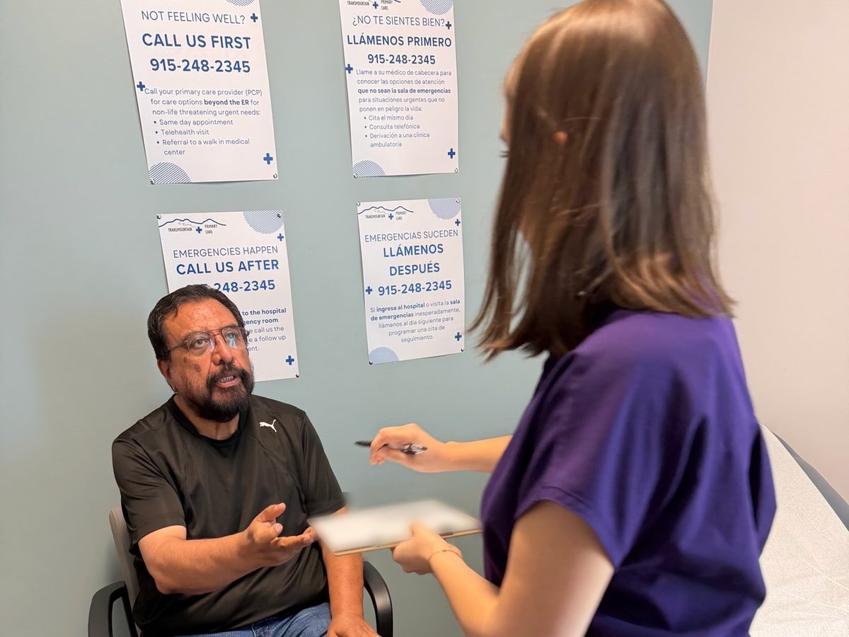 A team member handing a form to a patient at Transmountain Primary Care in El Paso